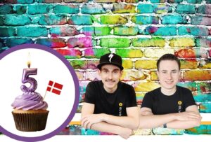 Alex og erwin med en fødselsdagskage foran en multifarvet væg